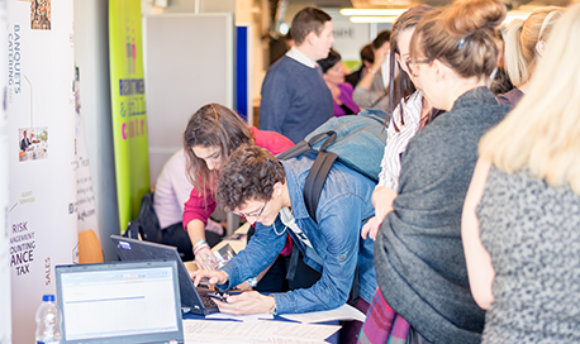 Students using a laptop at a busy recruitment fair, ֱ campus, Edinburgh