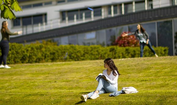 Students playing frisbee on the grass outside ֱ, Edinburgh