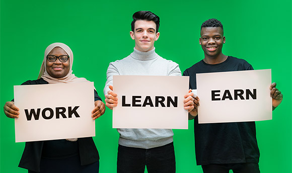 Three ֱ students holding signs with the words "Work", "Learn" and "Earn"