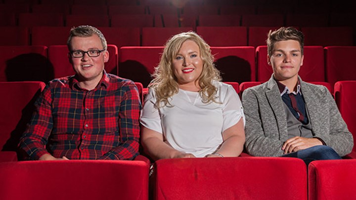 Three ֱ students sitting in plush red seats at the theatre