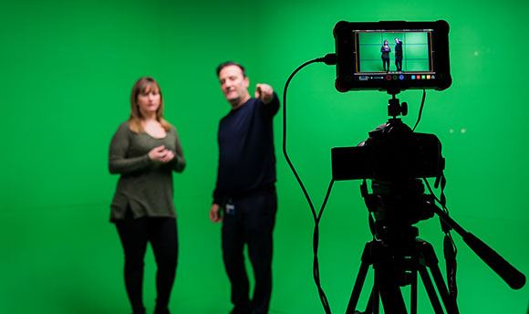 A ֱ student being briefed in front of a green screen