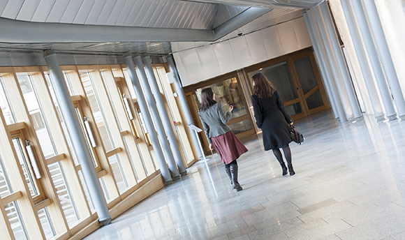 Two women walking down a corridor in ֱ hallway