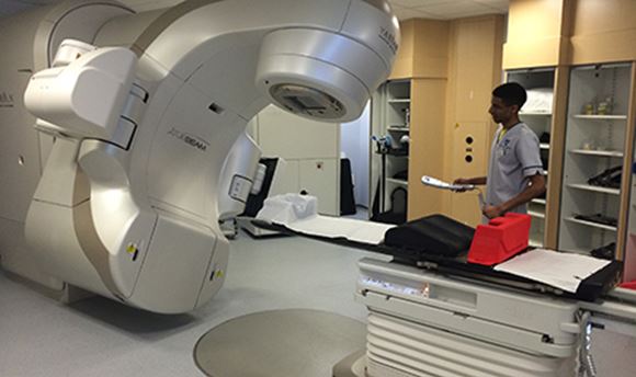 A ֱ student standing beside a Radiotherapy machine