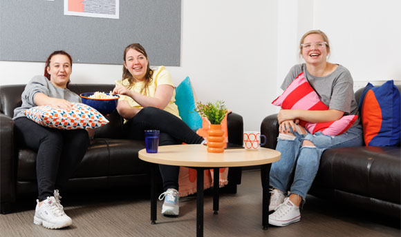 Three female students enjoy popcorn while watching a film in their ֱ Student Accommodation